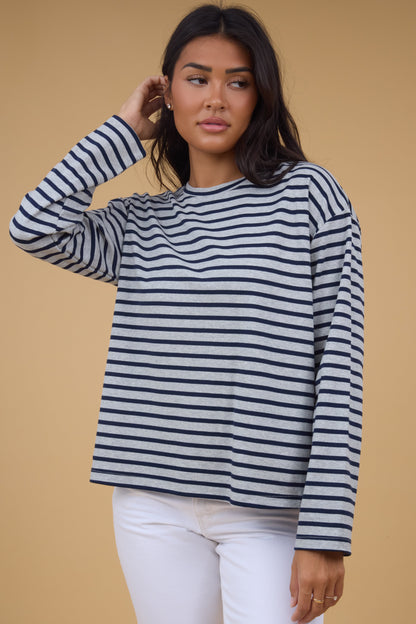 Young woman wearing a modest grey & navy stripe top with a crew neckline and long sleeves.
