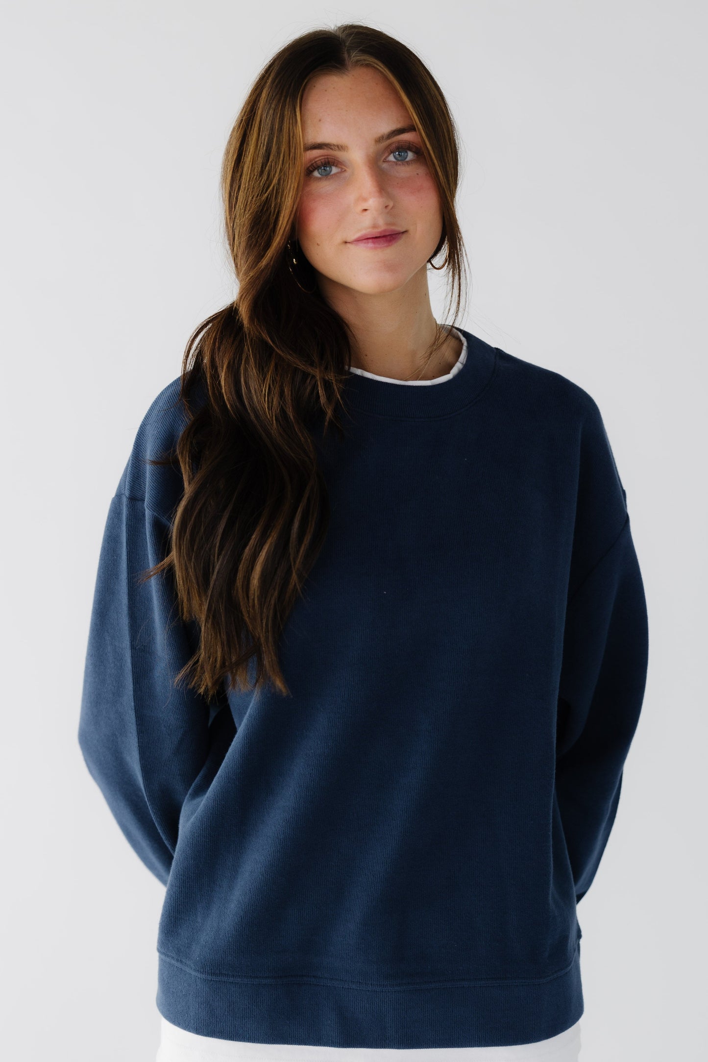 Woman wearing a navy oversized sweatshirt with long sleeves.