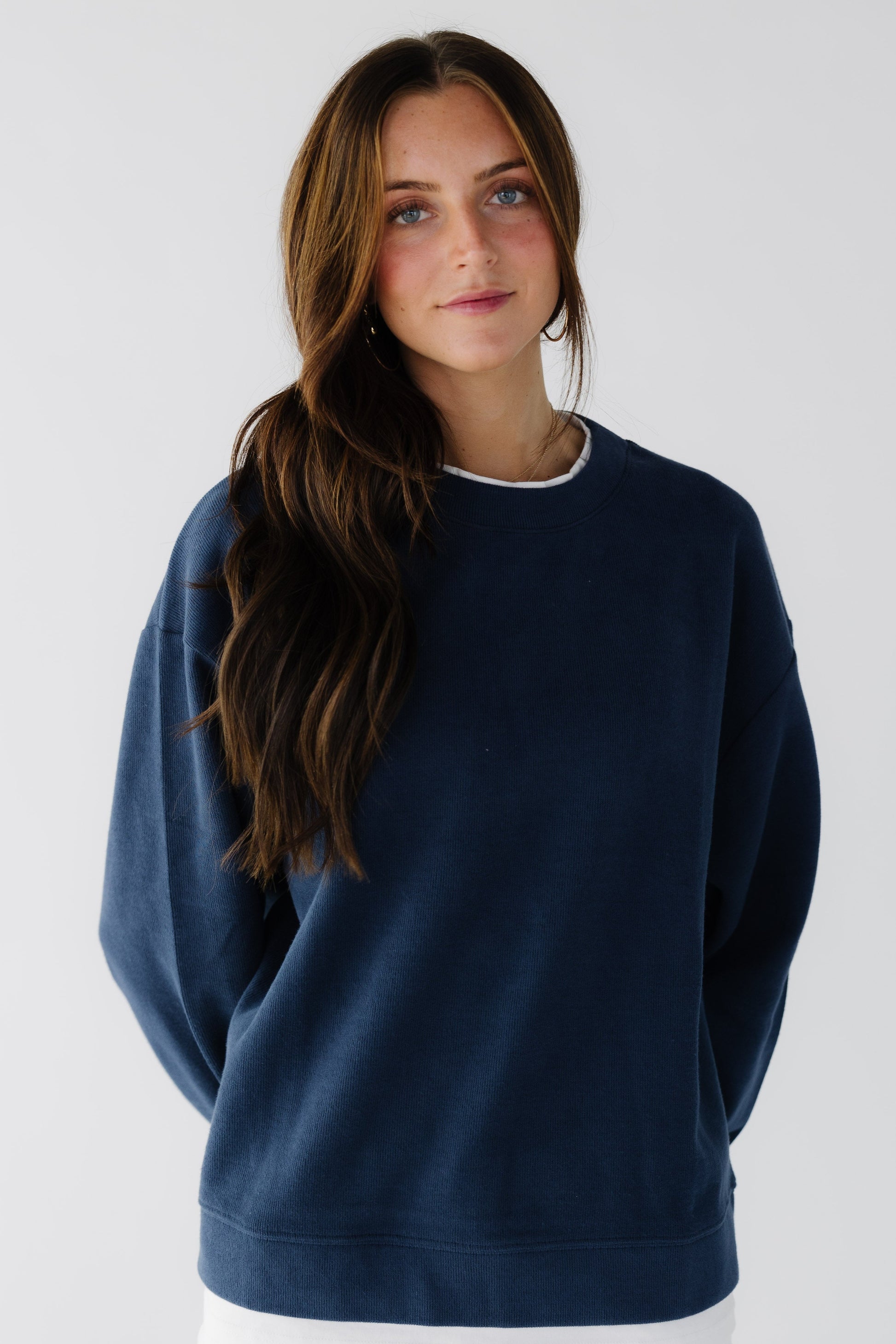 Woman wearing a navy oversized sweatshirt with long sleeves.