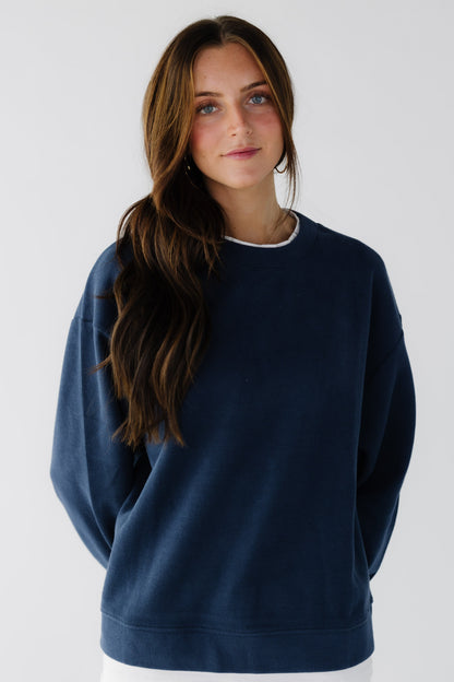 Woman wearing a navy oversized sweatshirt with long sleeves.