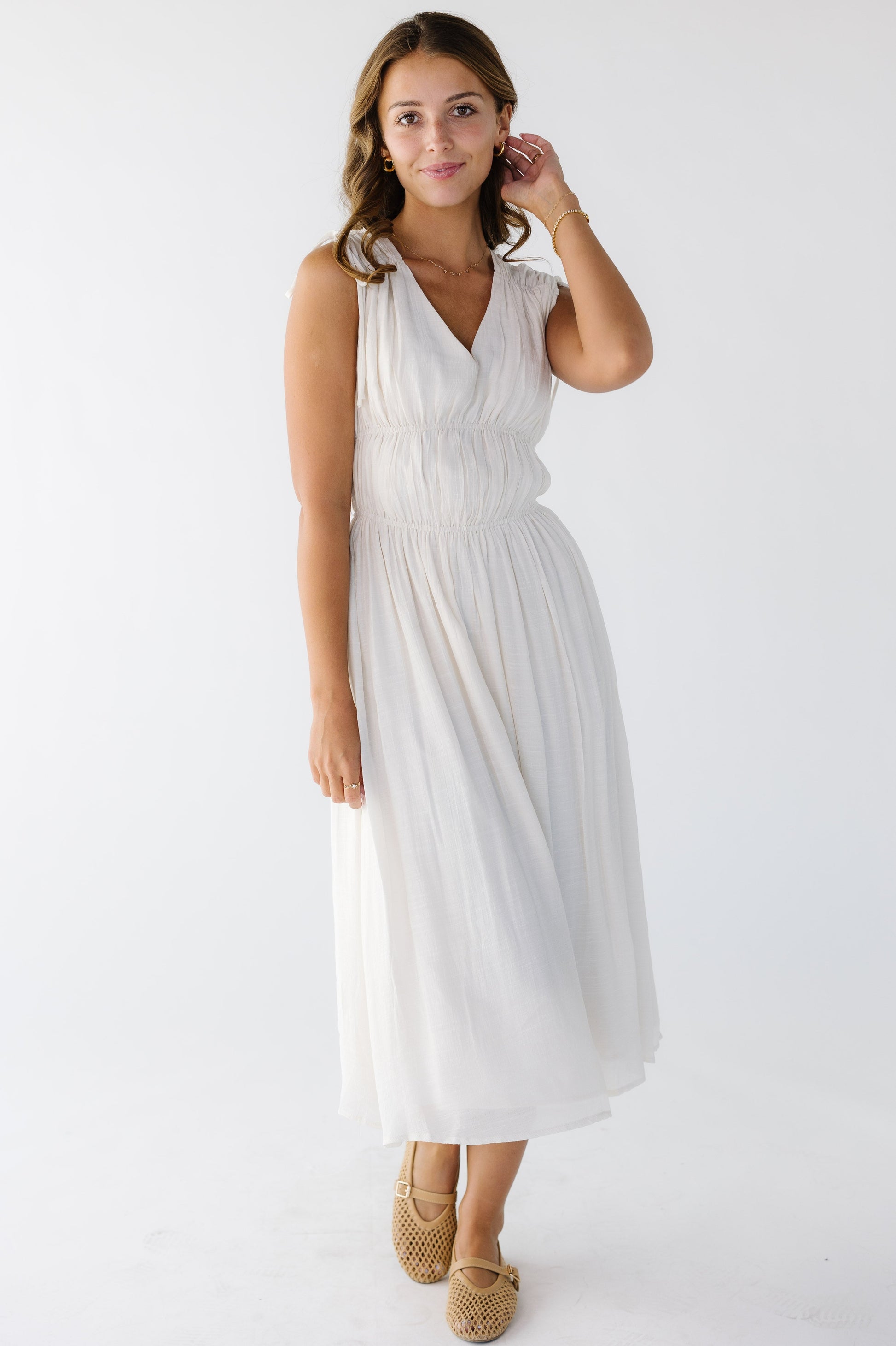Young woman wearing a modest off white midi dress with a V-neckline and bodice gathers.