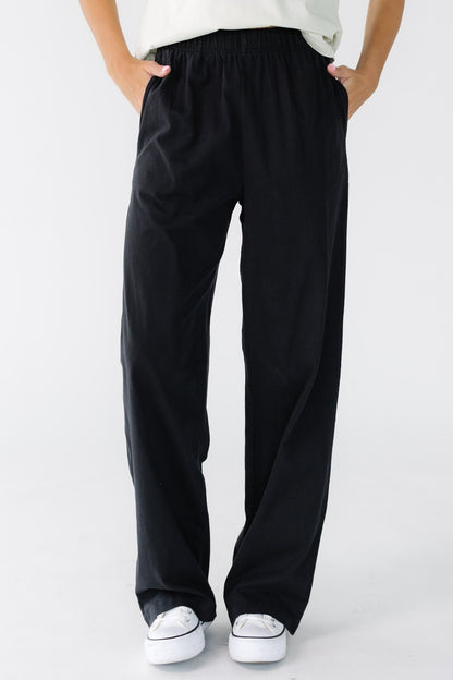 Young woman wearing a pair of black wide leg black pants with side pockets.