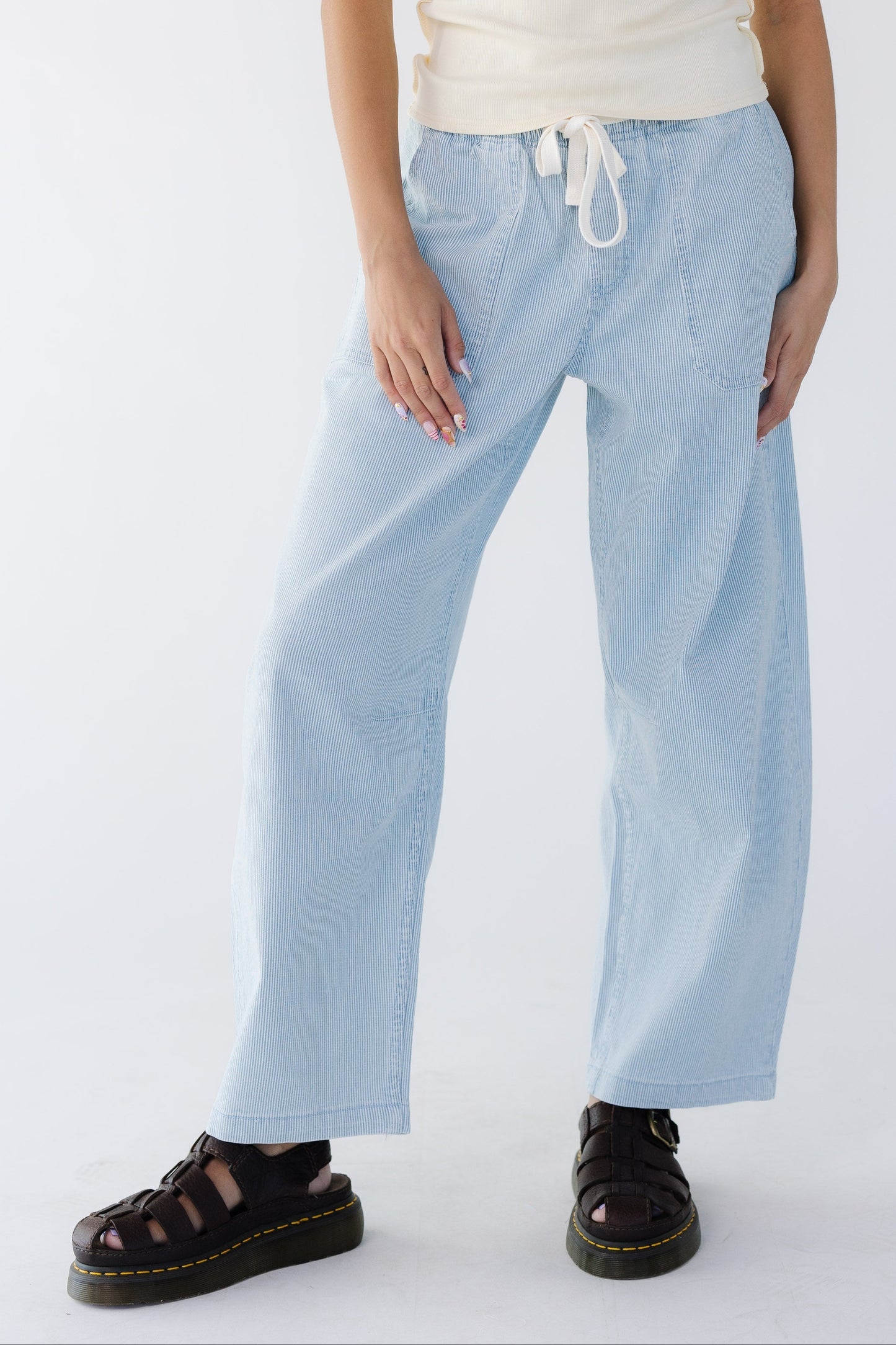 Young woman wearing a pair of blue and white pinstripe pants cut with a wide, loose leg.