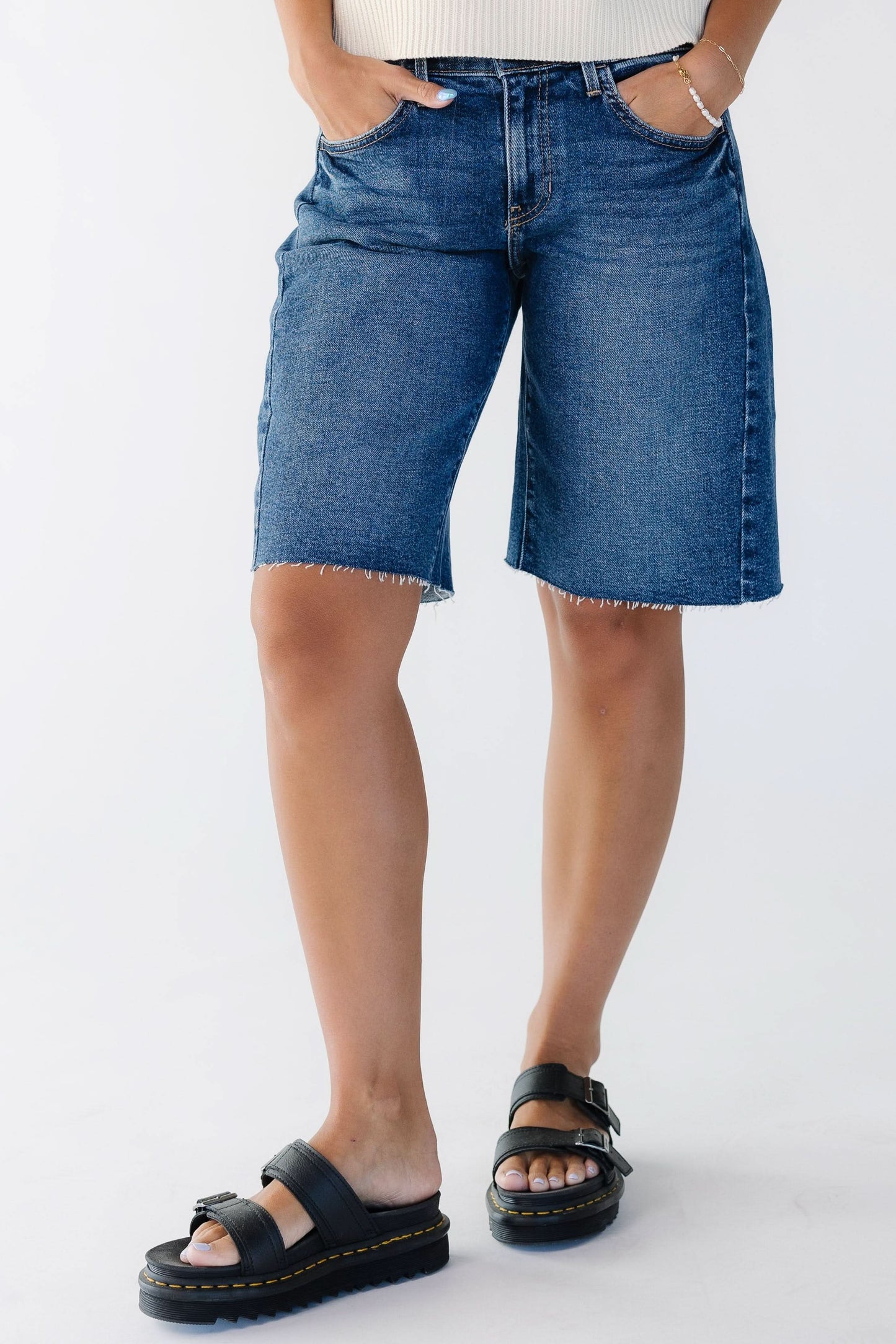 Young woman wearing a dark denim pair of shorts with scissor cut hems.
