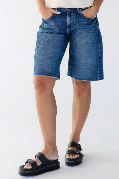 Young woman wearing a dark denim pair of shorts with scissor cut hems.