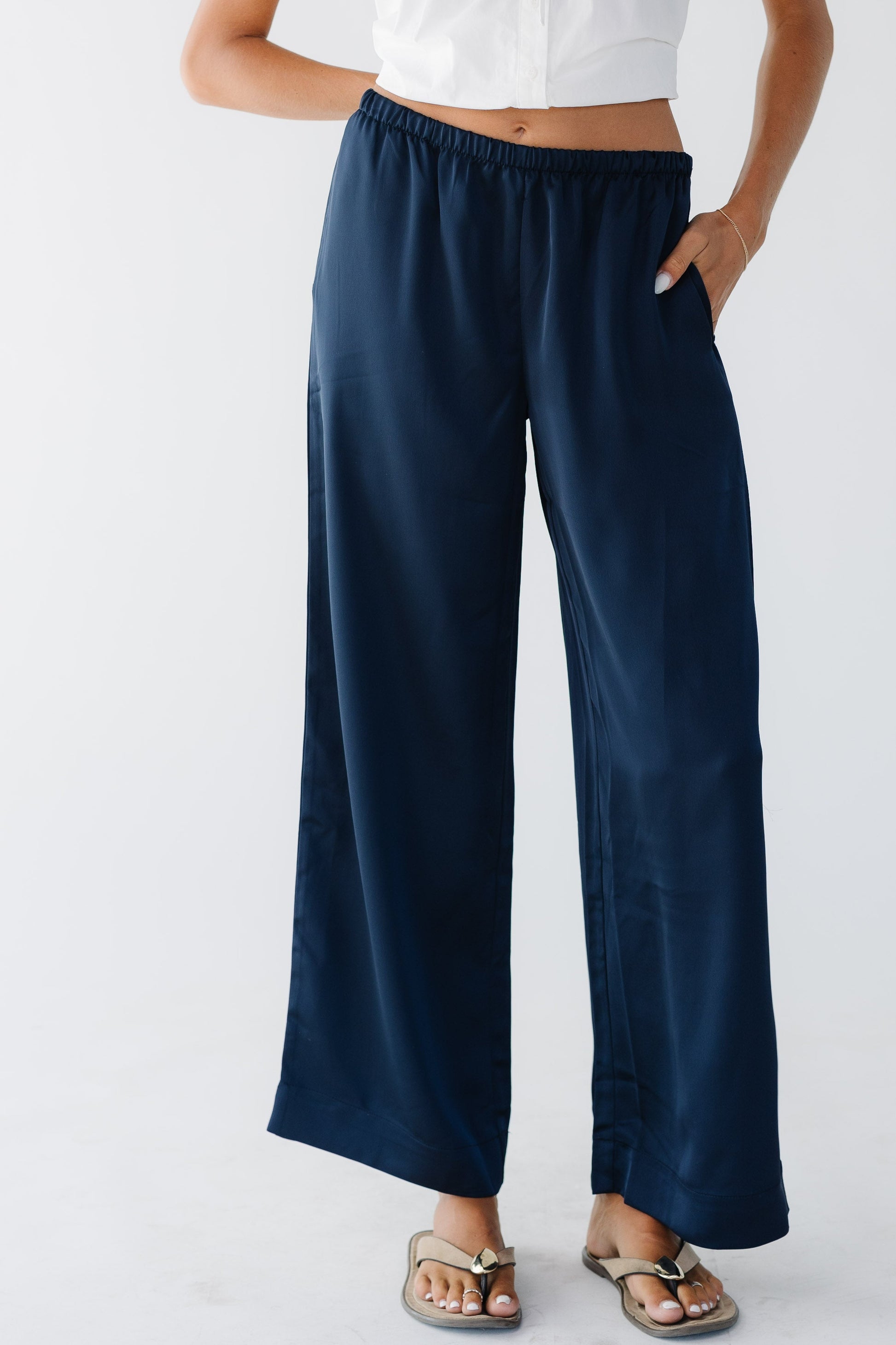 Young woman wearing a pair of wide leg satan pants with side pockets and an elastic waist.