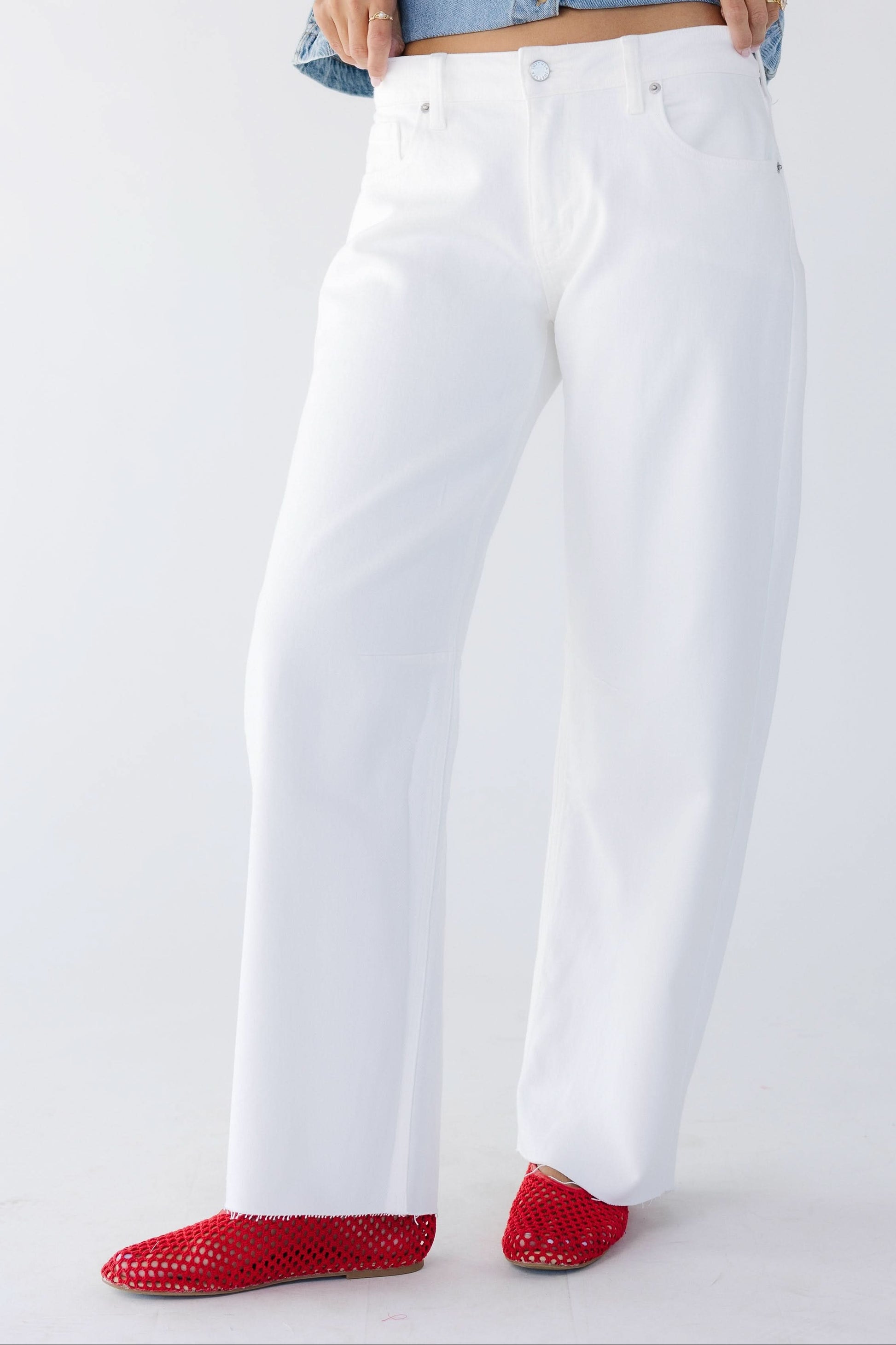 Woman wearing white jeans cut with a wide leg and scissor cut hems.