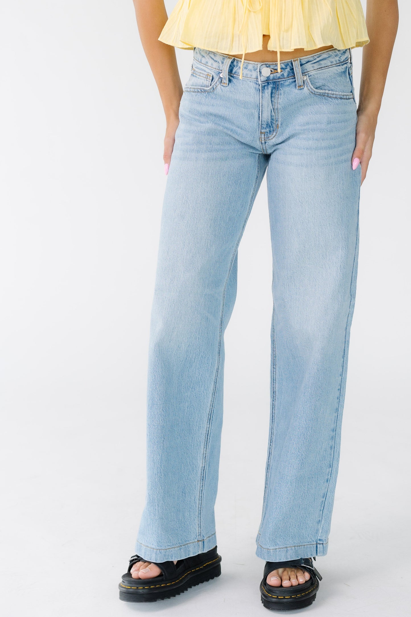 Woman wearing a pair of wide leg hemmed jeans.