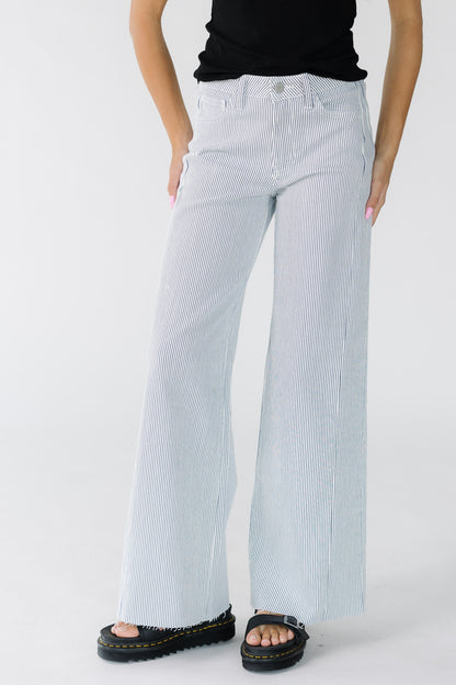 Woman wearing a pair of modest wide leg jeans in white with thin navy stripe with cut hems.