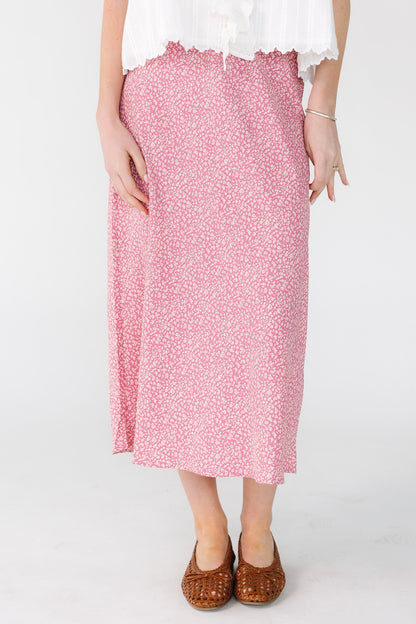 Woman wearing a modest A-line midi skirt in pink and white floral print.