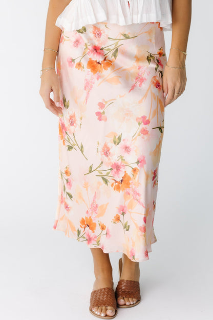 Woman wearing a pink floral A-line midi skirt.
