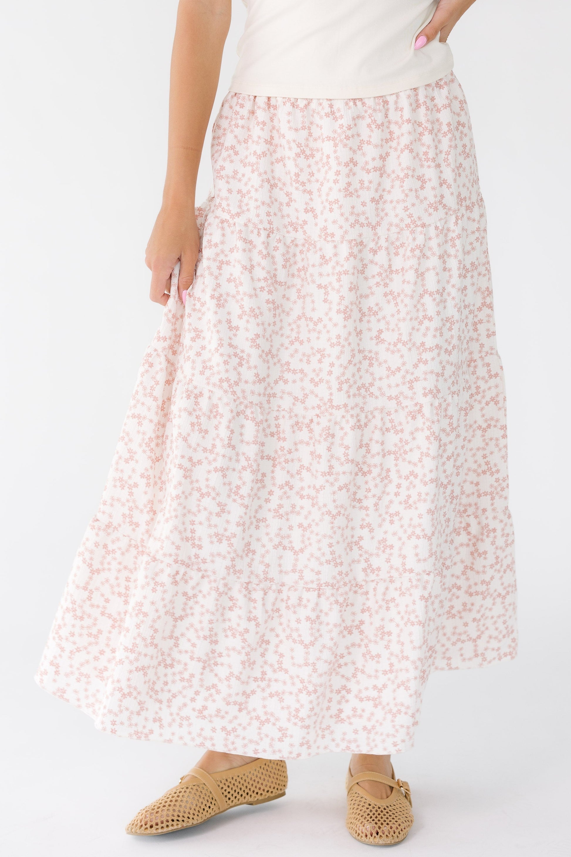 Woman wearing a modest pink and white floral tiered midi-maxi skirt.