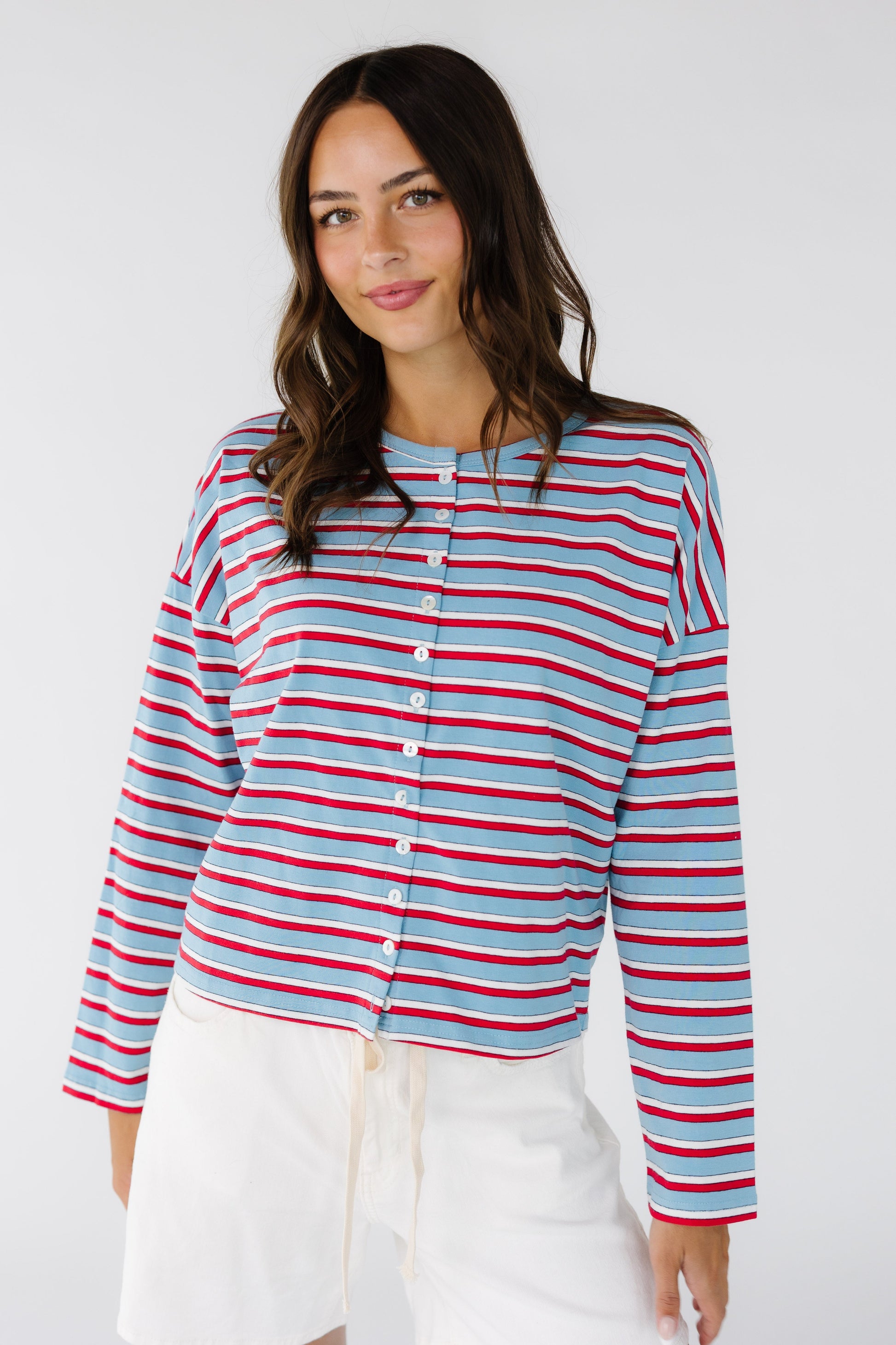Young woman wearing a modest stripe,  button down jersey cardigan with long sleeves in light blue, red and white stripe.