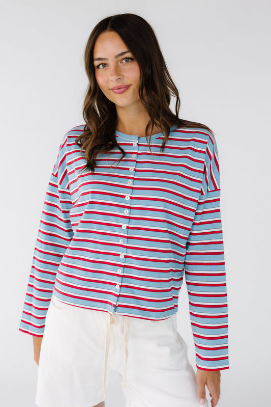 Young woman wearing a modest stripe,  button down jersey cardigan with long sleeves in light blue, red and white stripe.