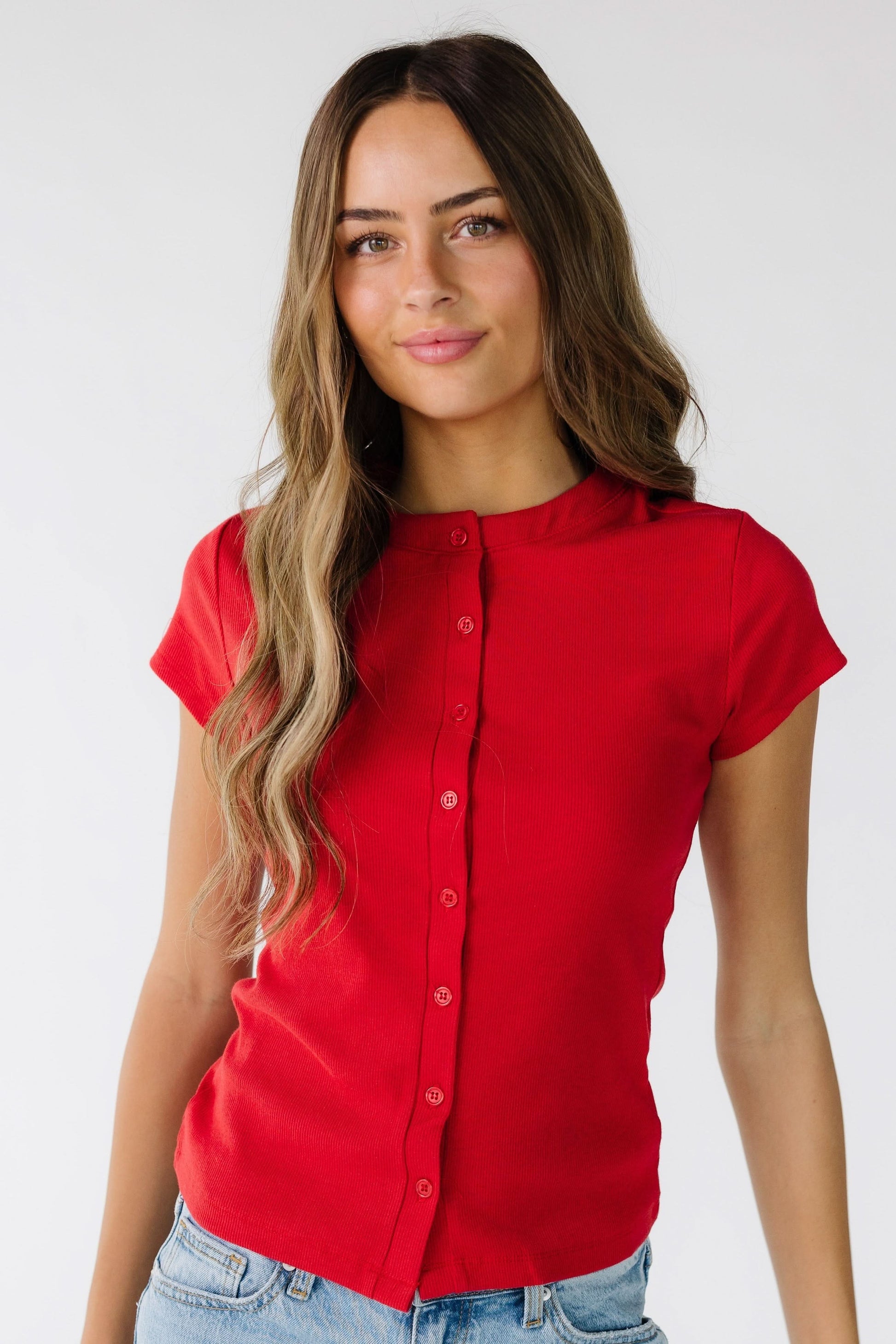 Young woman wearing  a red button down top with short sleeves.
