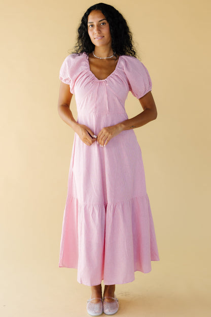 Woman wearing a very narrow red & white stripe midi-maxi dress with a close fitting bodice and a wide full skirt with a wide bottom ruffle.