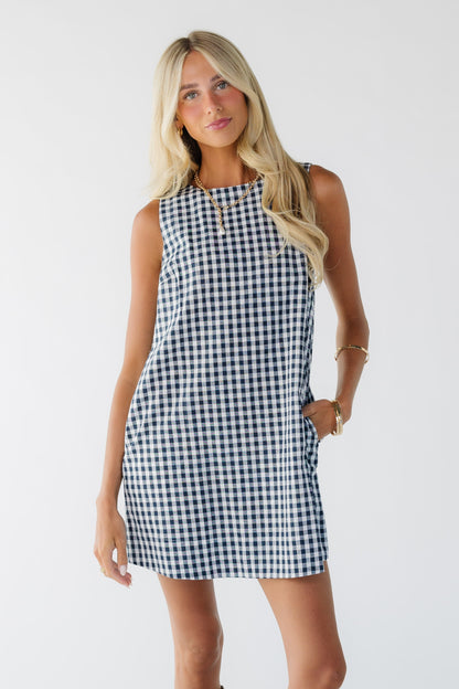 Young woman wearing a navy & white short shift dress with a round neckline.