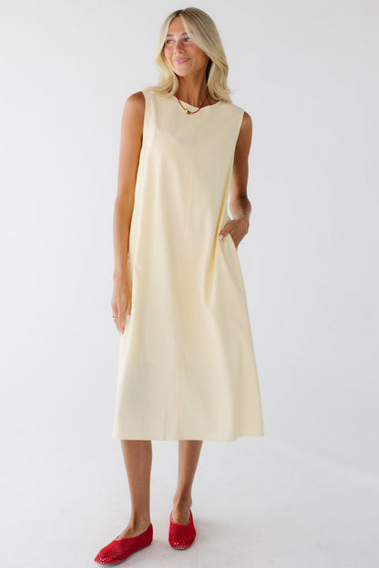 Young woman wearing a yellow sleeveless midi dress with side pockets