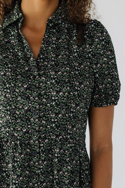 Close view of a teenage girl wearing a black floral, button down dress with short puff sleeves.