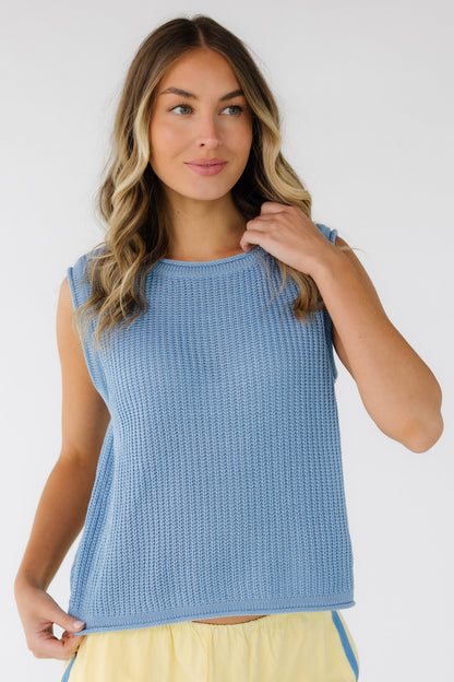 Woman wearing a light blue rib knit sleeveless sweater vest with rolled hems.