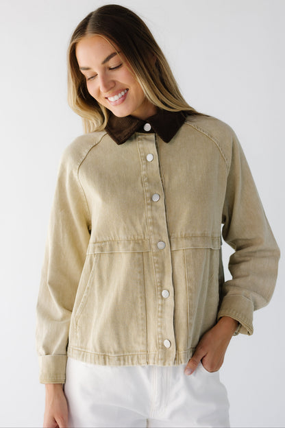 Woman wearing a tan jacket with large front pockets, metal buttons, long sleeves and a brown corduroy collar.