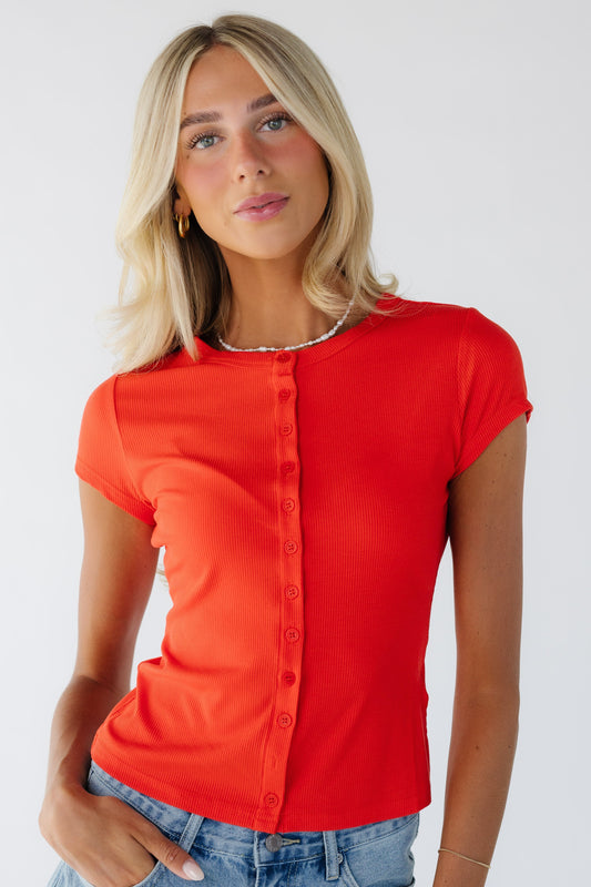 Young woman wearing a modest red button down top with a round neckline and short sleeves.