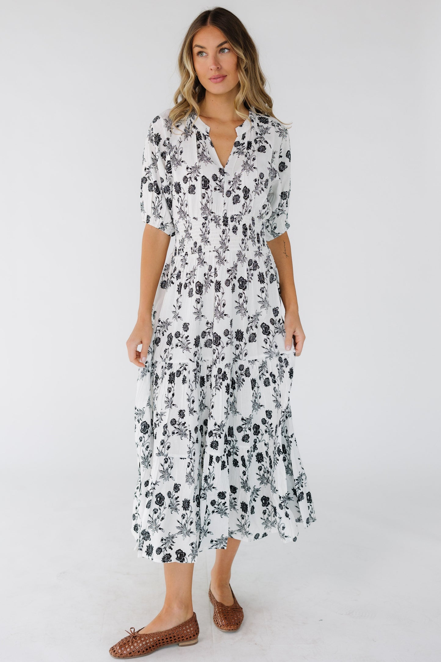 Woman wearing a flowy black & white midi dress with a V-neckline and elbow length sleeves.