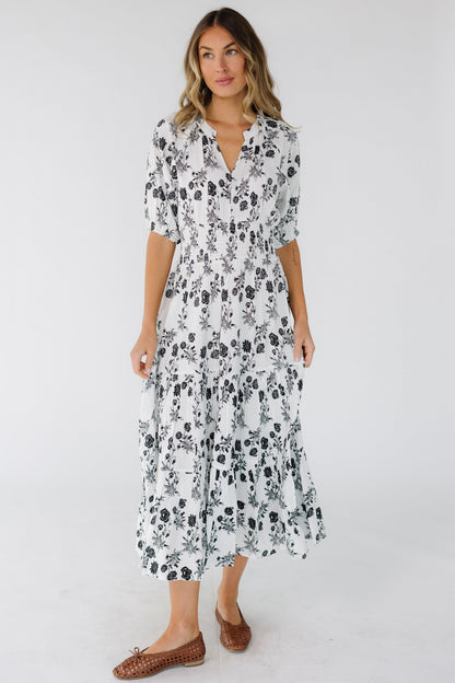 Woman wearing a flowy black & white midi dress with a V-neckline and elbow length sleeves.
