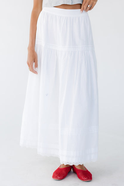 Woman wearing a white midi-maxi skirt with lace & pleat details.