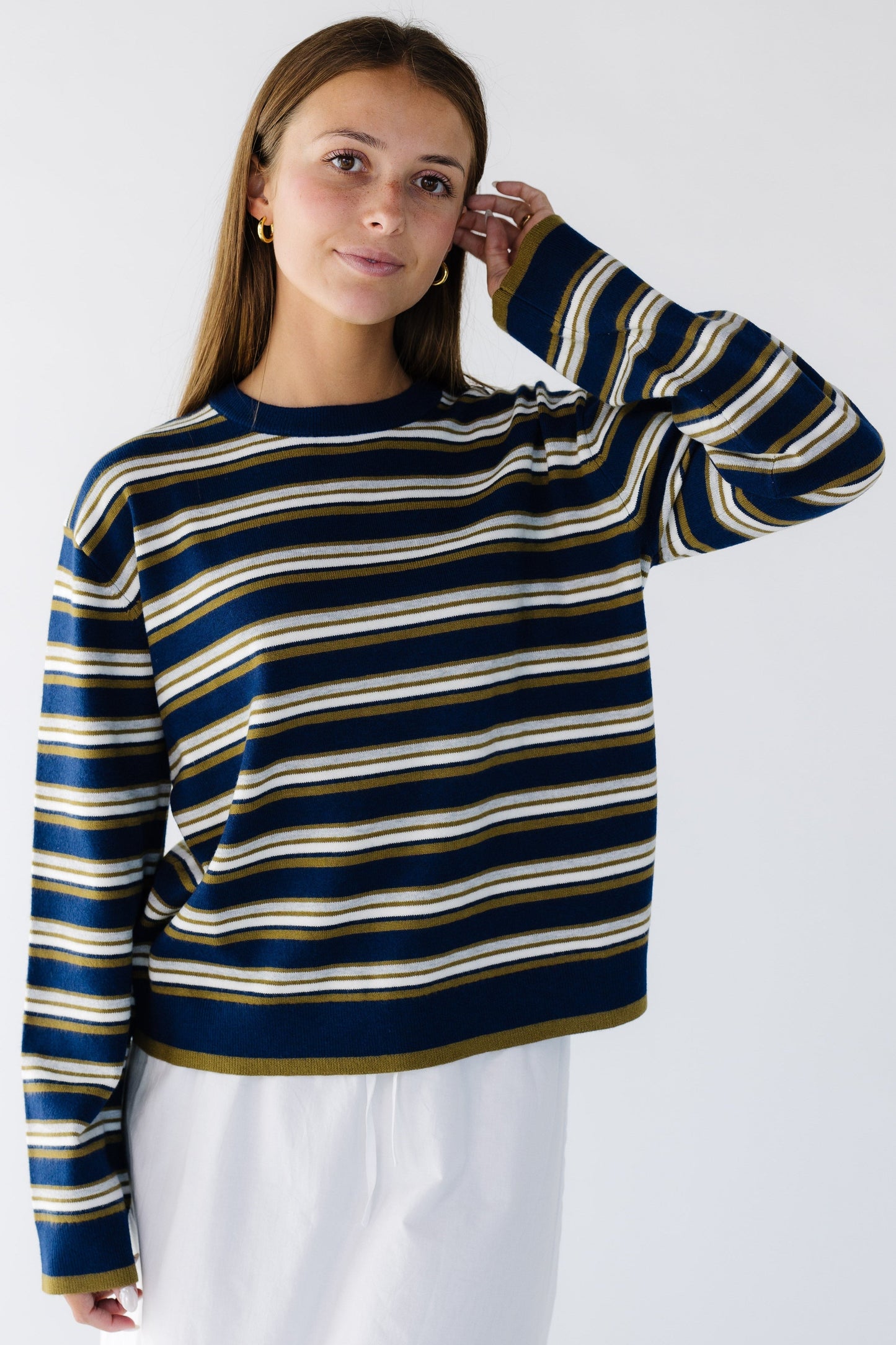 Woman wearing a wide, loose fitting stripe sweaterwith long wide sleeves.