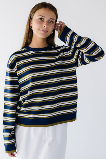 Woman wearing a wide, loose fitting stripe sweaterwith long wide sleeves.