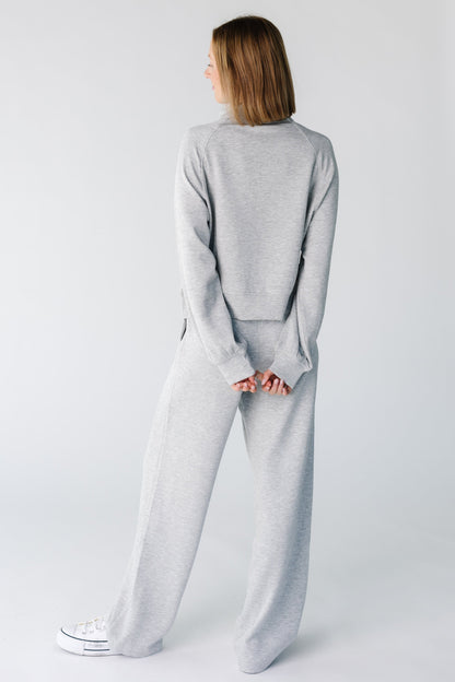 Back view of a woman wearing a light grey lounge set with long sleeves and long, wide cut bottoms