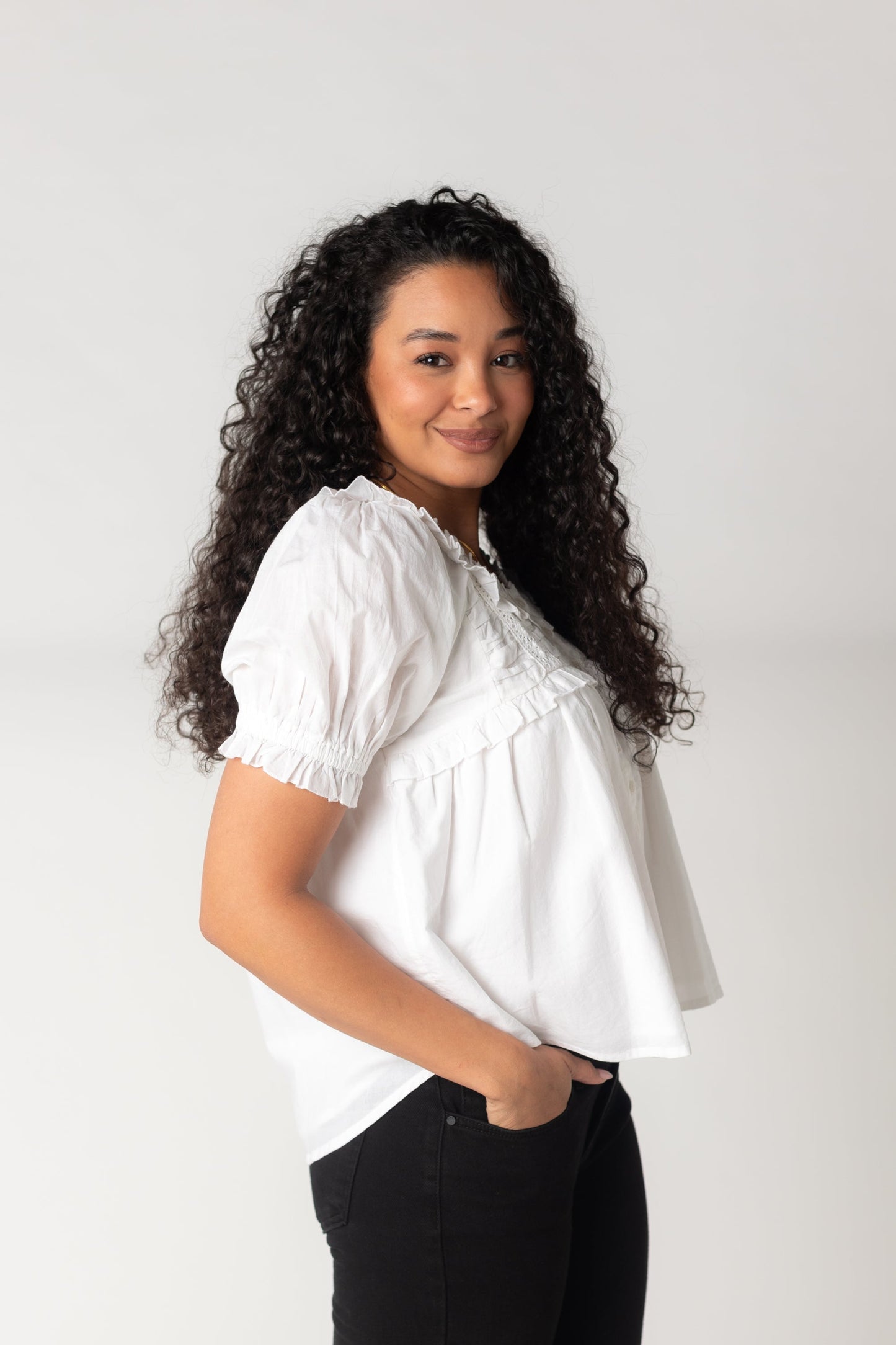 Side view of white ruffle top with short puff sleeves