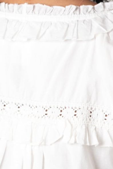 Very close up view of white lace and ruffle top