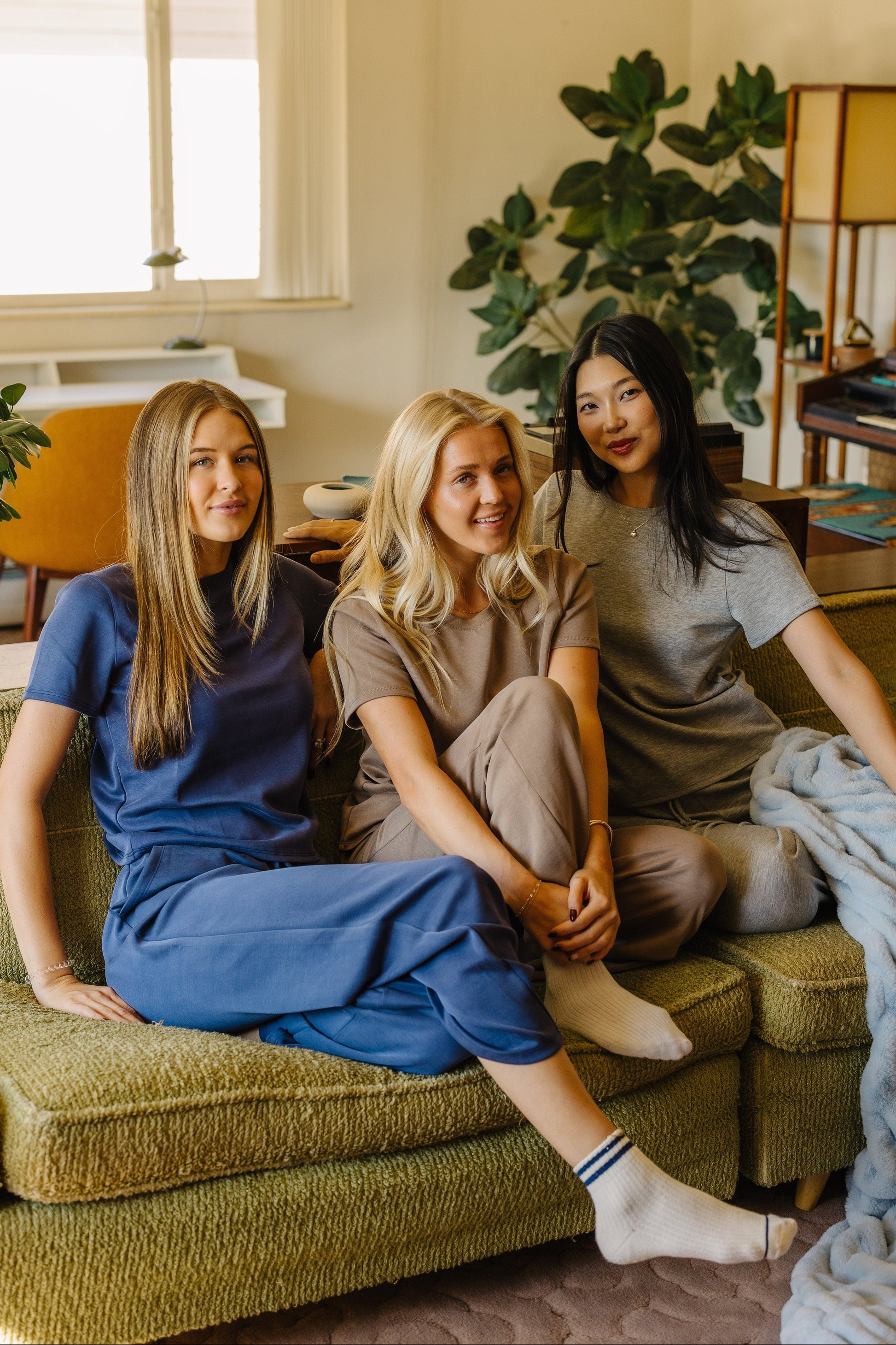 3 women wearing lounge sets in blue, tan and grey