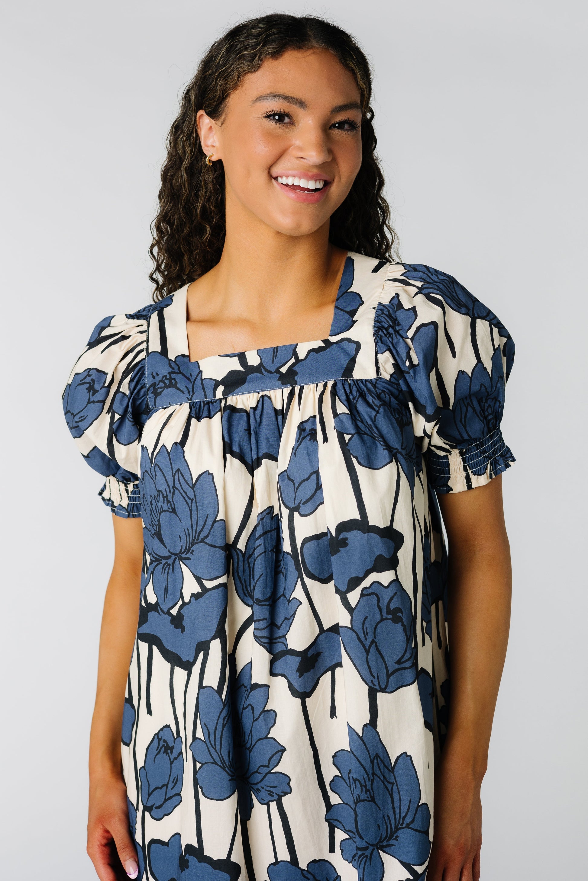 Close view of a woman wearing a cream and blue floral midi dress