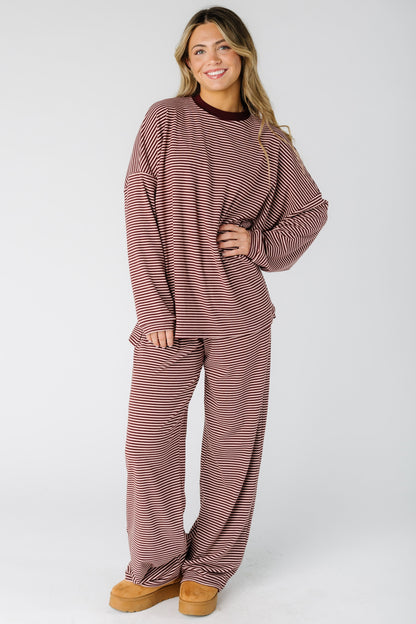 Woman wearing a loose fitting lounge set with long sleeves in burgundy and  pink stripe