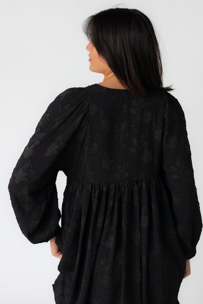 Back view of black jacquard mini dress with long sleeves