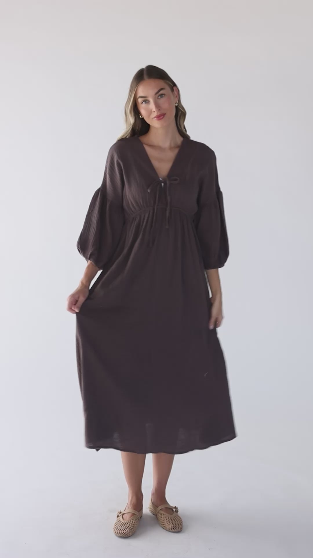 Video of a women wearing a brown midi dress with three quarter length sleeves