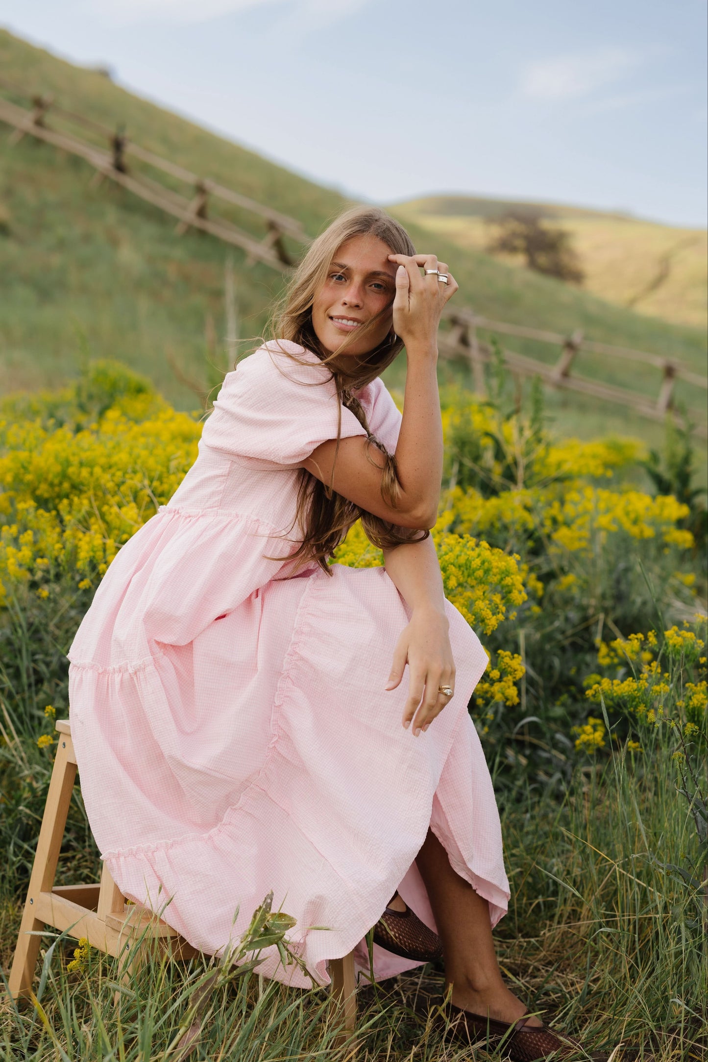Young woman wearing a modest loose fitting pink gingham midi dress with balloon sleeves.