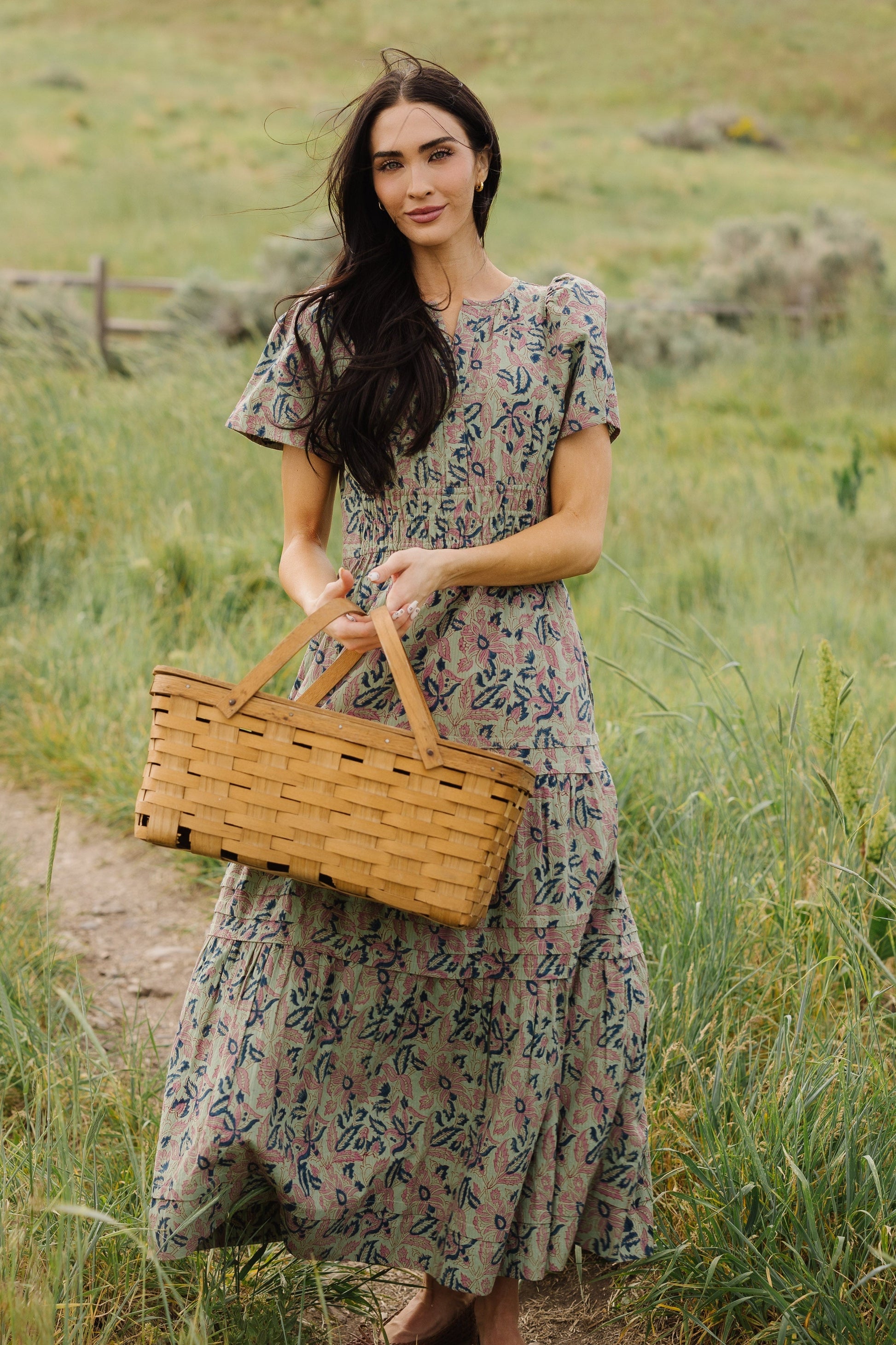Young woman wearing a modest grean floral midi-maxi dress with short sleeves and a tiered and gathered skirt.